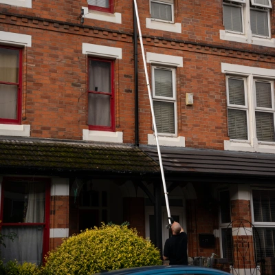 Technician vacuum-clearing gutters on a Derby property
